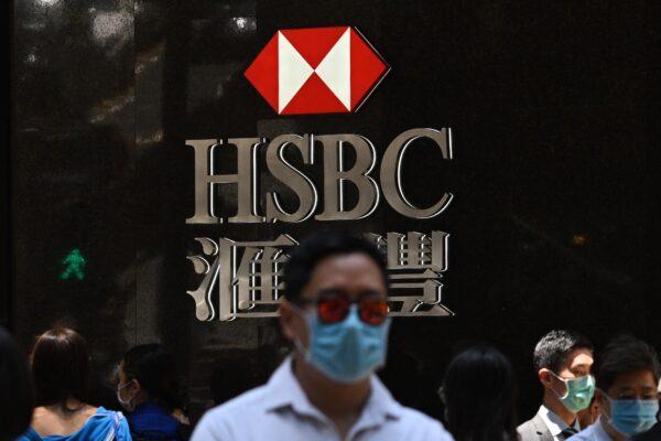 Pedestrians wear face masks as they walk past HSBC signage outside a branch of the bank in Hong Kong on April 28, 2020. (Anthony Wallace/AFP/Getty Images)