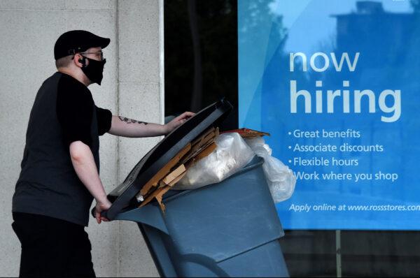 A man wearing a face mask walks past a sign "Now Hiring" in front of a store amid the coronavirus pandemic in Arlington, Va., on May 14, 2020. (Olivier Douliery/AFP/Getty Images)