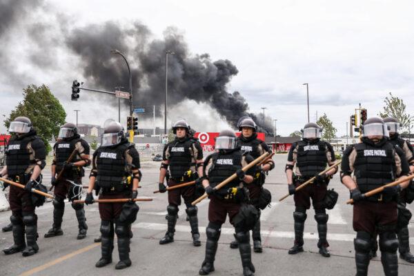 State Police stand guard as smoke billows from buildings that continue to burn in the aftermath of a night of protests and violence following the May 25 death of George Floyd, in Minneapolis, Minn., on May 29, 2020. (Charlotte Cuthbertson/The Epoch Times)