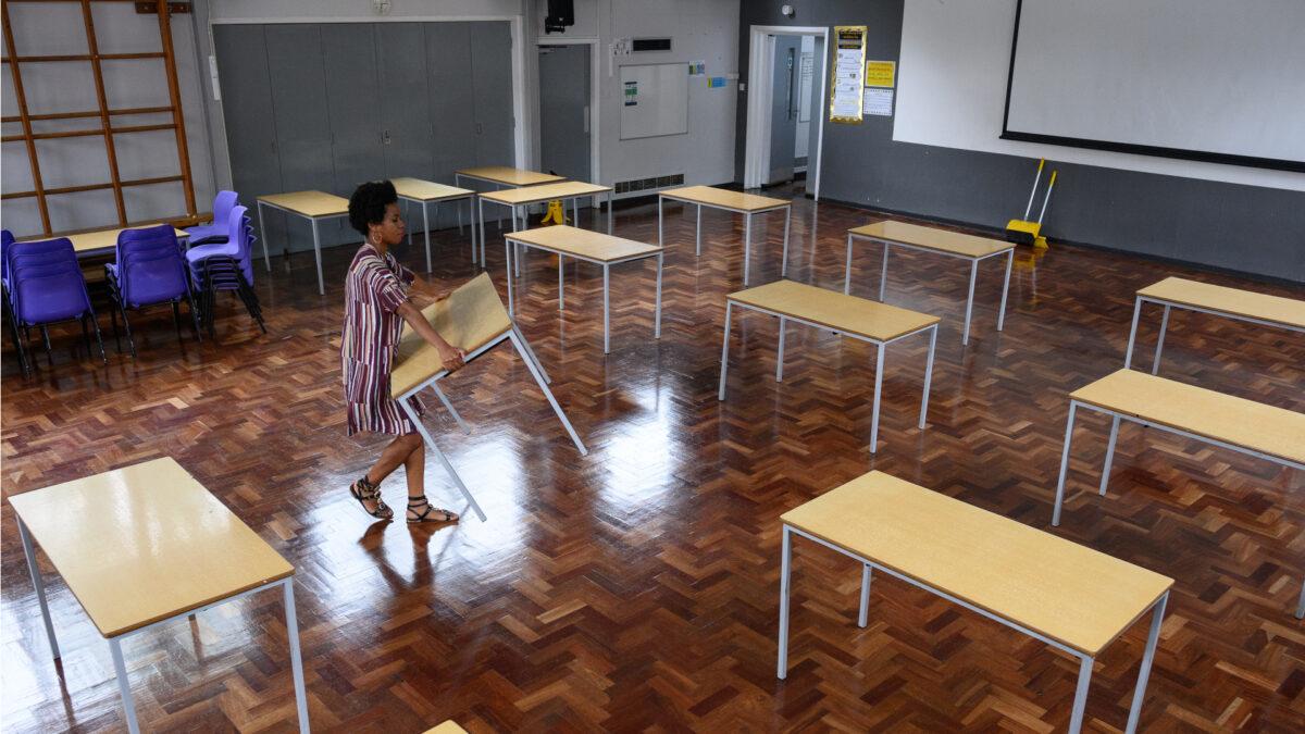 Teacher Muriel Thompson carries a desk into the temporary classroom within the school hall, ahead of the return of more students from Reception and Year 6 of Muswell Hill Primary School in London on June 3, 2020. (Leon Neal/Getty Images)