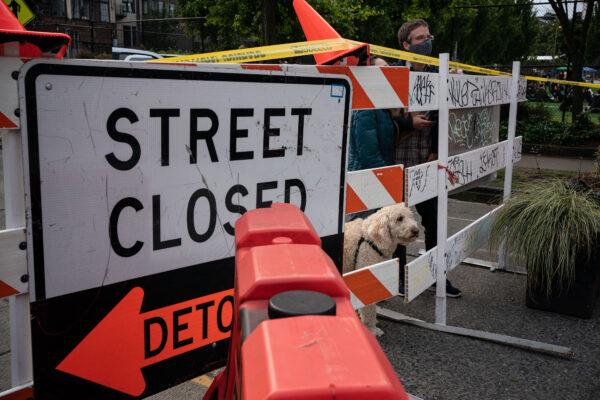 People peer through a barrier with their dog at an entrance to the so-called "Capitol Hill Autonomous Zone,” in Seattle, Wash., on June 10, 2020. (David Ryder/Getty Images)