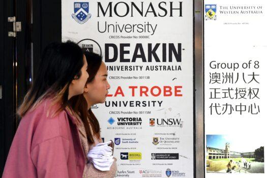People walk past signage for Australian universities in Melbourne’s central business district on June 10, 2020, (William West/AFP via Getty Images)