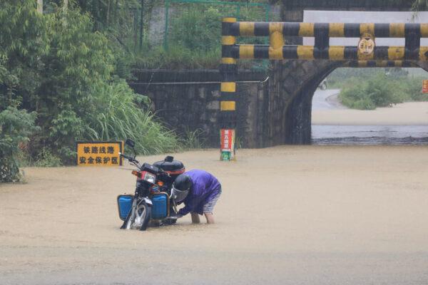 A man is checking his motorcycle amid floodwaters in Rong'an County in China's southern Guangxi region on June 10, 2020. (STR/AFP via Getty Images)