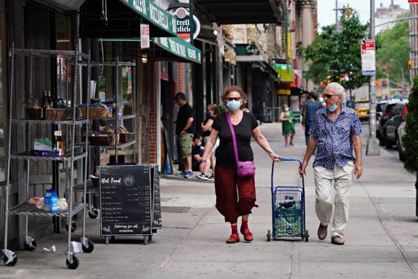 People wearing protective masks walk through Little Italy during the CCP virus pandemic in New York City on May 29, 2020. (Cindy Ord/Getty Images)