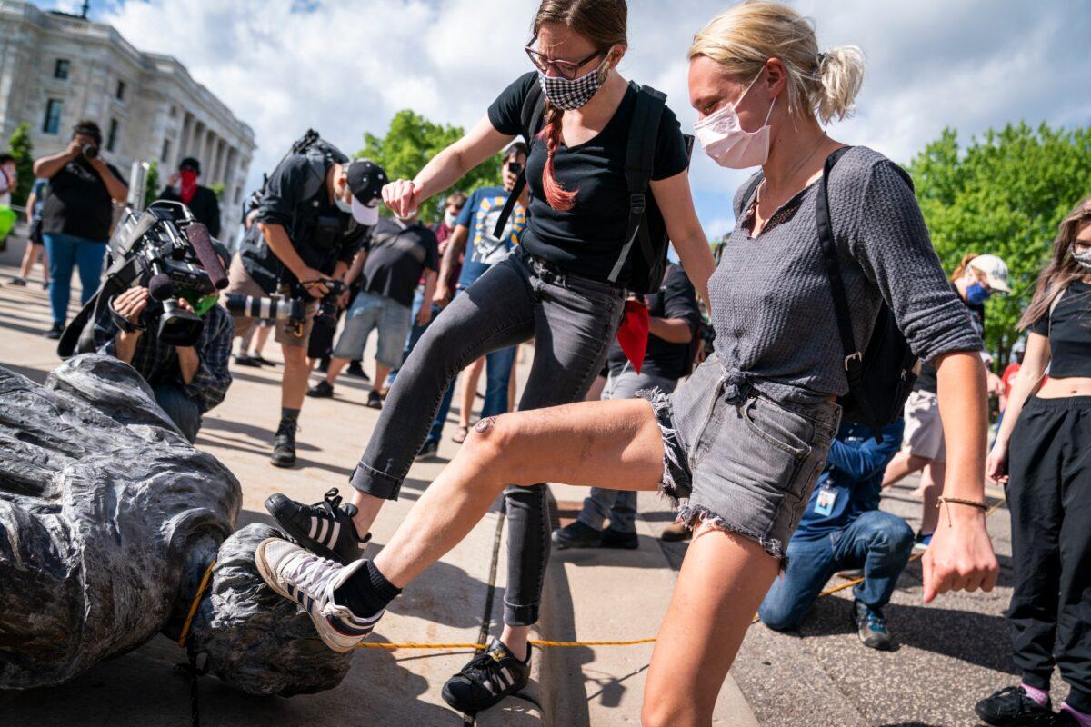People take turns stomping the Christopher Columbus statue after it was toppled in front of the Minnesota State Capitol in St. Paul, Minn., on June 10, 2020. (Leila Navidi/Star Tribune via AP)