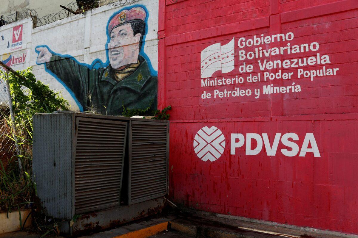 The logo of the Venezuelan state oil company PDVSA is seen next to a mural depicting Venezuela's late President Hugo Chavez at a gas station in Caracas, Venezuela, on March 2, 2017. (Carlos Garcia Rawlins/Reuters)