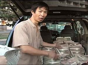 Lu Ping shown in front of his Dodge Grand Caravan filled with bundles of Truth Magazine, an anti-Falun Gong newspaper that is being called hate propaganda. (NTDTV)