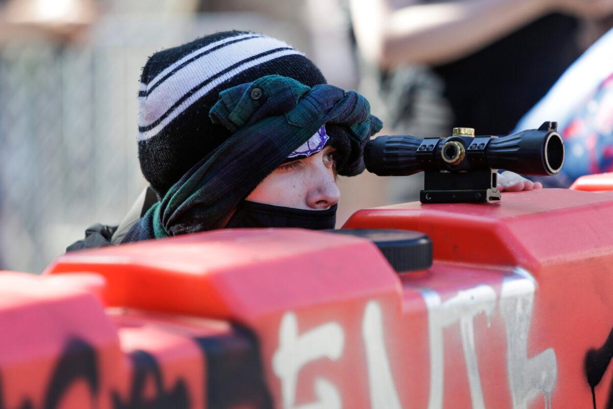 A protester uses a scope on top of a barricade to look for police approaching the newly created Capitol Hill Autonomous Zone in Seattle, Wash., on June 11, 2020. (Jason Redmond/AFP via Getty Images)