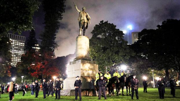 Police officers stand guard around the statue of British explorer Captain James Cook, in Sydney, Australia, June 12. (Loren Elliott/Reuters)