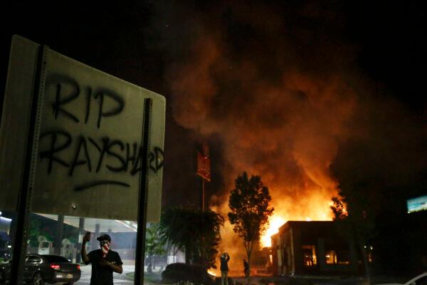 "RIP Rayshard" is spray-painted on a sign as flames engulf a Wendy's restaurant during protests in Atlanta, Ga., on June 13, 2020. (AP Photo/Brynn Anderson)