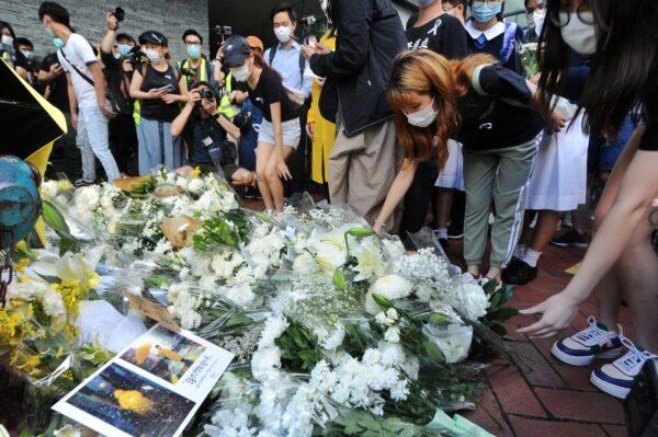 People lay down flowers to mourn the death of a local protester, near the Pacific Place mall in Admiralty, Hong Kong, on June 15, 2020. (Song Bilung/The Epoch Times)