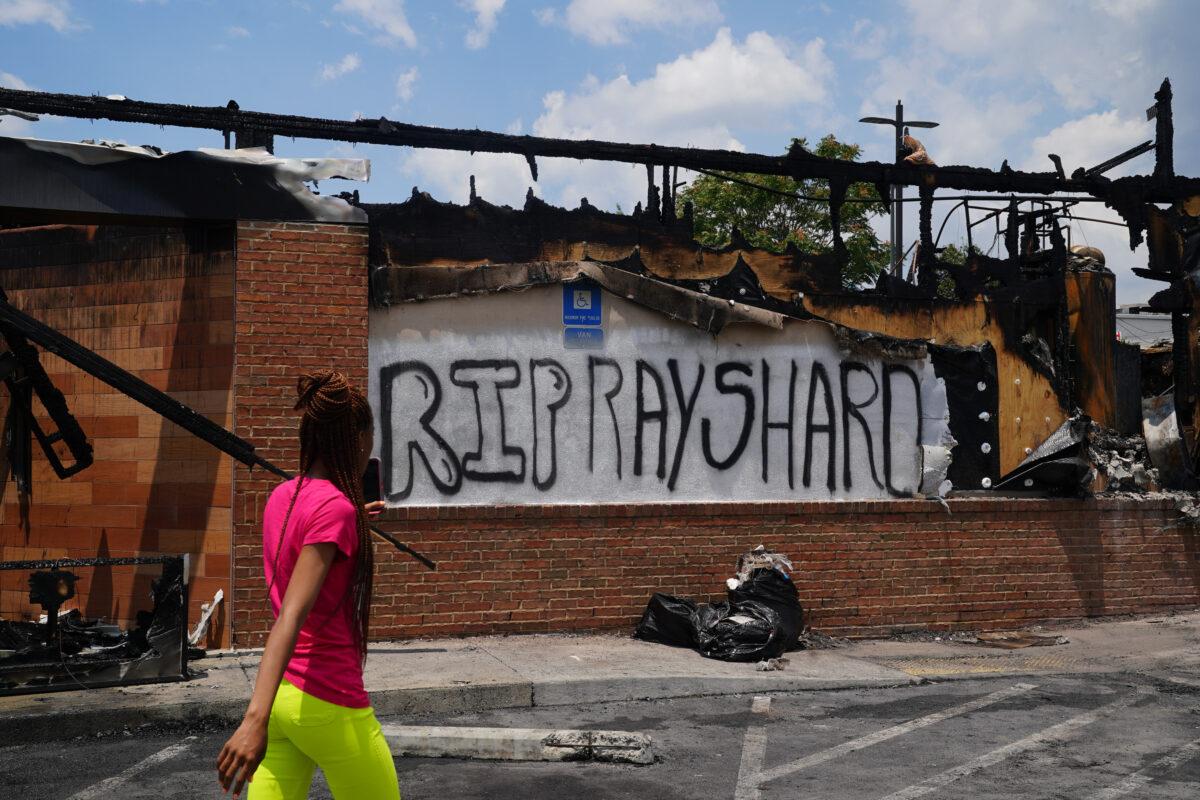A woman uses her cell phone to document the damage to a burned Wendys restaurant in Atlanta, Ga., on June 14, 2020. (Elijah Nouvelage/AFP via Getty Images)