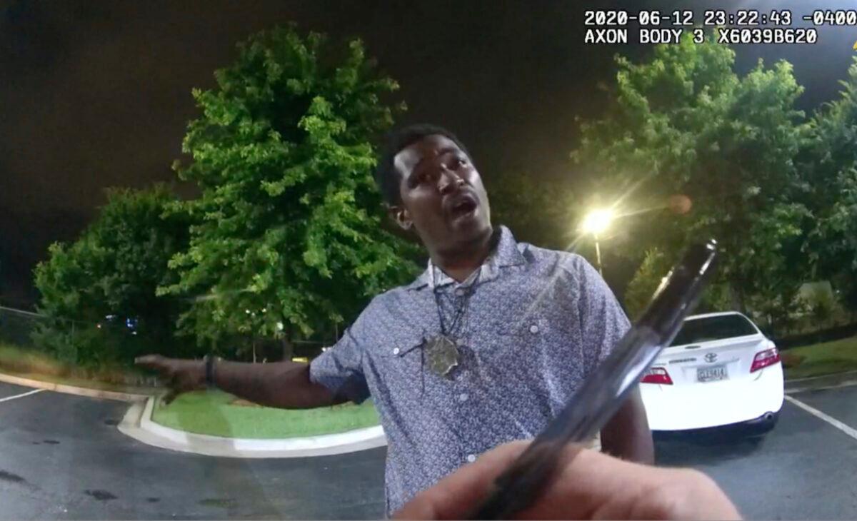A still image from video shows Rayshard Brooks speaking with Officer Garrett Rolfe as Rolfe writes notes during a field sobriety test in the parking lot of a Wendy's restaurant in Atlanta, Ga., late June 12, 2020. (Atlanta Police Department via AP)