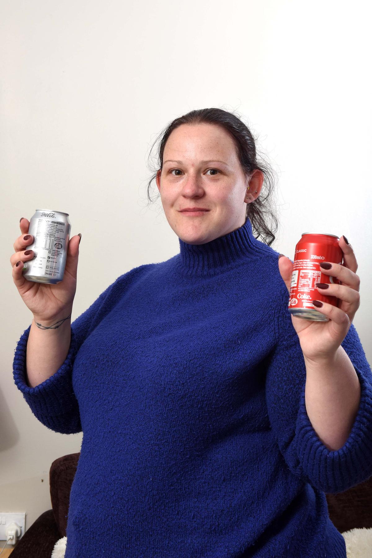 Elizabeth Perkins with two cans: one of diet cola, which she is allergic to, and one of regular cola, which she can have. (Caters News)