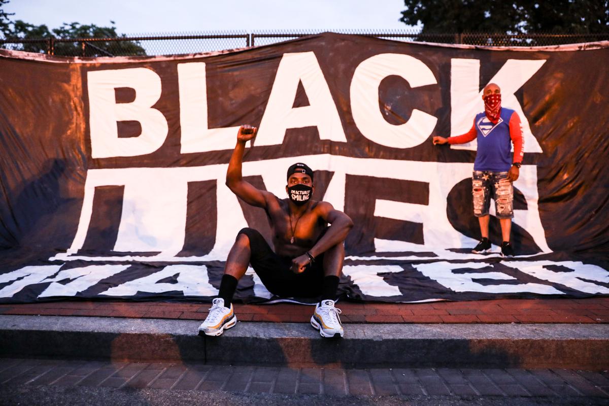 Protesters pose in front of a Black Lives Matter sign near the White House following the May 25 death of George Floyd in police custody, in Washington on June 6, 2020. (Charlotte Cuthbertson/The Epoch Times)