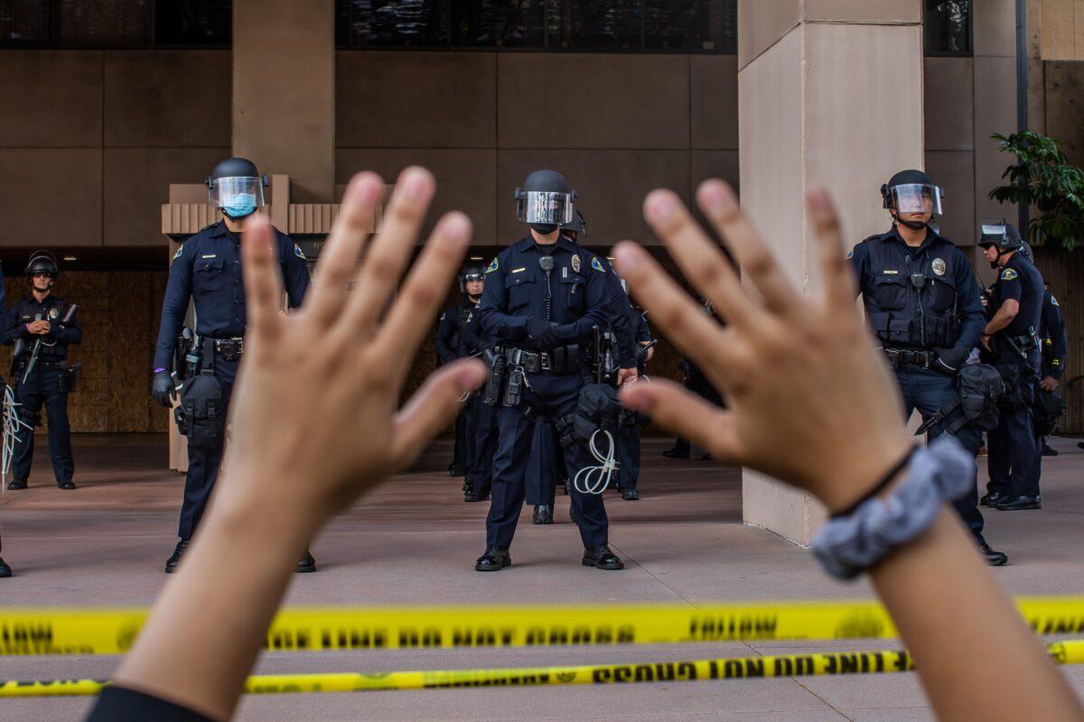 A demonstrator at a protest over the death of George Floyd holds her hands up while she kneels in front of the police at City Hall in Anaheim, Calif., on June 1, 2020. (Apu Gomes/AFP/Getty Images)