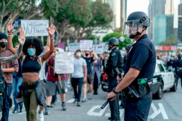 Protesters march past LAPD officers during a demonstration over the death of George Floyd in downtown Los Angeles, Calif., on June 6, 2020. (Kyle Grillot/AFP via Getty Images)