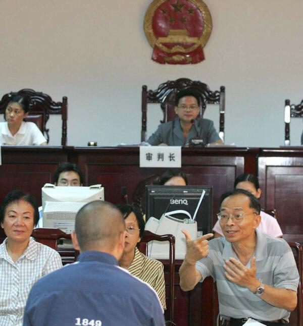 Court translators use sign-language to assist a hearing-impaired prisoner in a Guangzhou courtroom, in southern China's Guangdong province on Aug. 18, 2004. (STR/AFP via Getty Images)