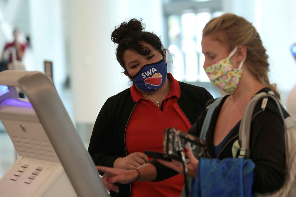 A Southwest Airlines employee wears a protective mask while assisting a passenger at Los Angeles International Airport (LAX) during the outbreak of the CCP virus in Los Angeles, Calif., on May 23, 2020. (Patrick T. Fallon/Reuters)