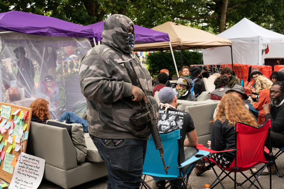 A man walks by the Conversation Cafe while carrying a firearm in the police-free zone known as the Capitol Hill Autonomous Zone (CHAZ) in Seattle, Wash., on June 15, 2020. (David Ryder/Getty Images)