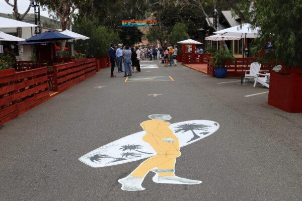A depiction of a surfer adorns the street in the newly opened promenade at Laguna Beach, Calif., on June 15, 2020. (Jamie Joseph/The Epoch Times)