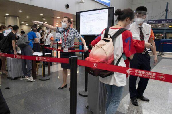 Airline employees redirect a traveler at a checkpoint for passengers from high-risk areas to present their CCP virus test results before checking in for their flight at the Beijing Capital Airport terminal 2 in Beijing, China, on June 17, 2020. (Ng Han Guan/AP Photo)