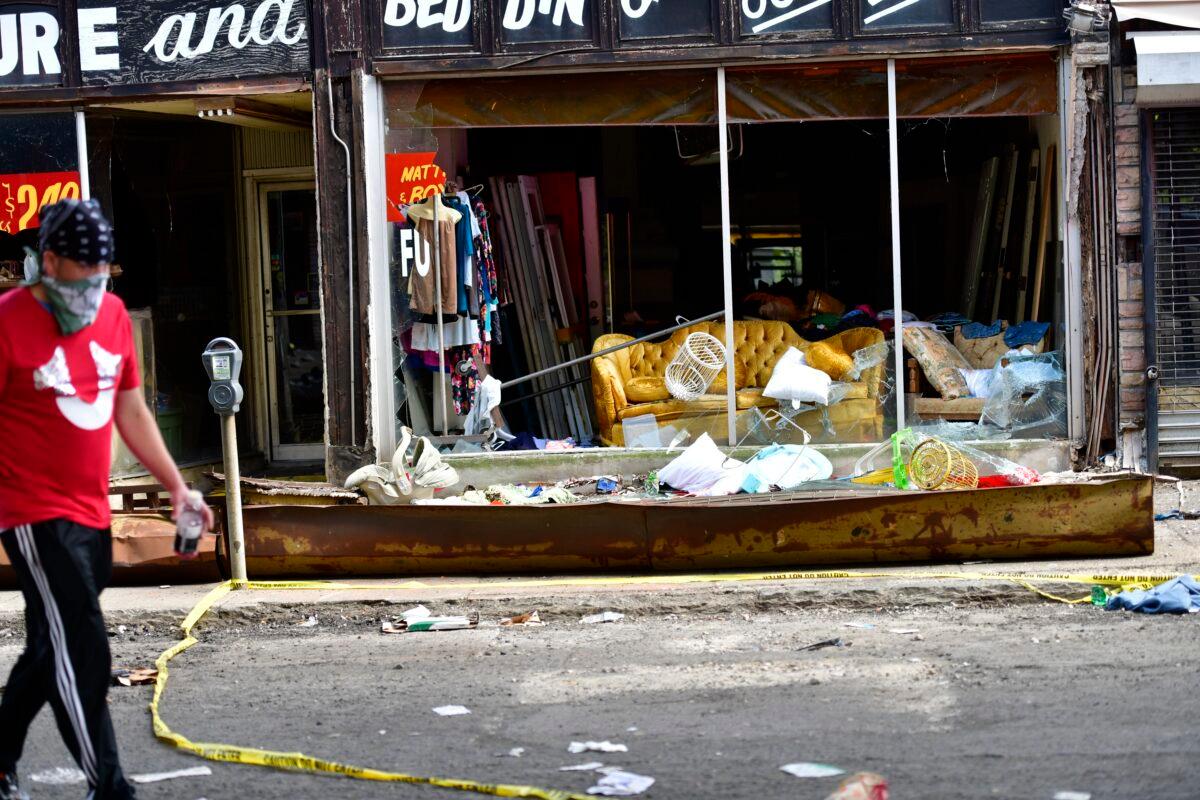 A masked man walks past a looted furniture store during a protest over the death of George Floyd, in Philadelphia, Penn., on May 31, 2020. (Mark Makela/Getty Images)