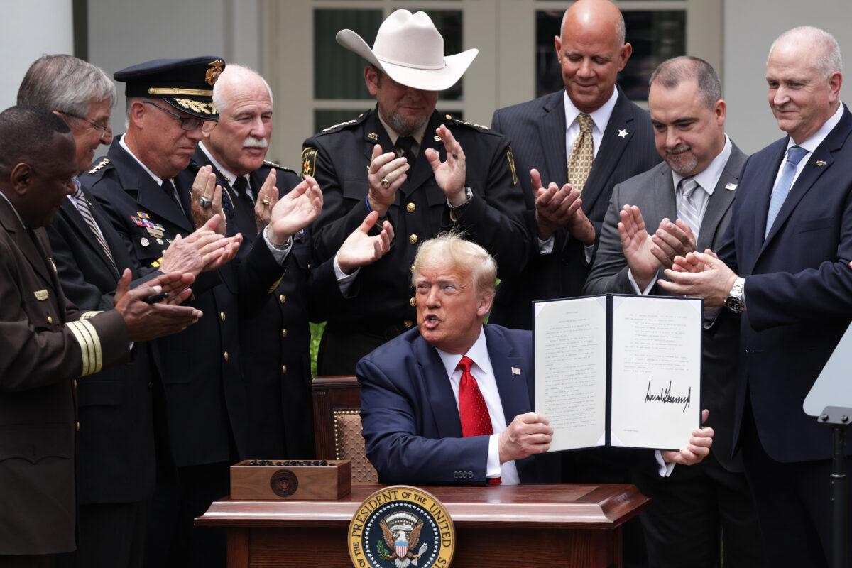 Surrounded by members of law enforcement, President Donald Trump holds up an executive order he signed on “Safe Policing for Safe Communities” during an event in the Rose Garden at the White House in Washington on June 16, 2020. (Alex Wong/Getty Images)