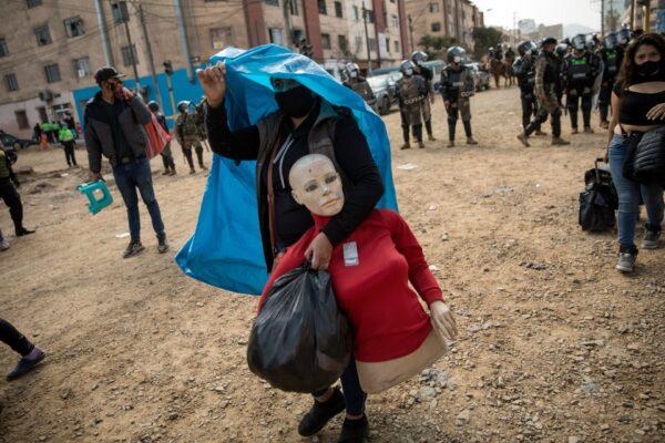 A street vendor walks away with her mannequin during a police operation to evict a group of street vendors who came out to sell their products, ignoring lockdown measures to curb the spread of the CCP virus, in La Victoria district, in Lima, Peru, on June 16, 2020. (Rodrigo Abd/AP Photo)