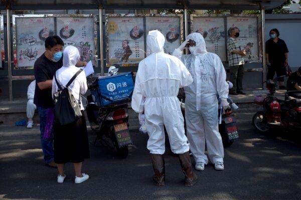 Medical staff members in full protective gear stand outside the Guangan sports center to assist people who live near or who have visited the Xinfadi Market, a wholesale food market where a new COVID-19 coronavirus cluster has emerged, for testing in Beijing on June 16, 2020. (Noel Celis/AFP via Getty Images)