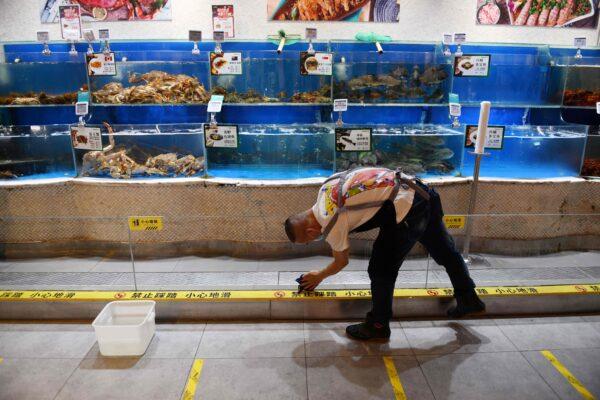 A worker cleans glass in the seafood section of a supermarket in Beijing, China, on June 17, 2020. (Greg Baker/AFP via Getty Images)