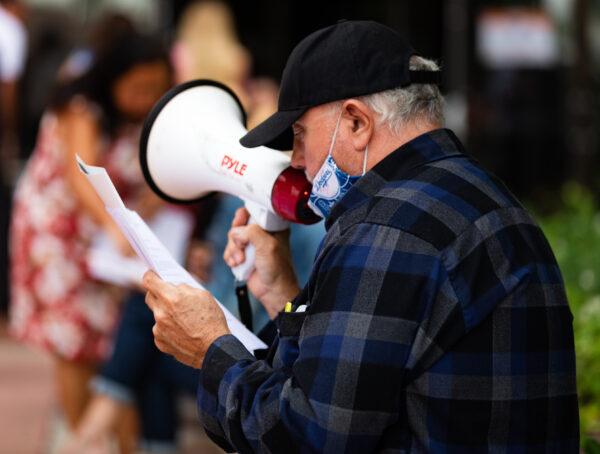 A protester with a bullhorn reads a list of names of people who have died from COVID-19 outside the Orange County Board of Supervisors' weekly session in Santa Ana, Calif., on June 16, 2020. (John Fredricks/The Epoch Times)