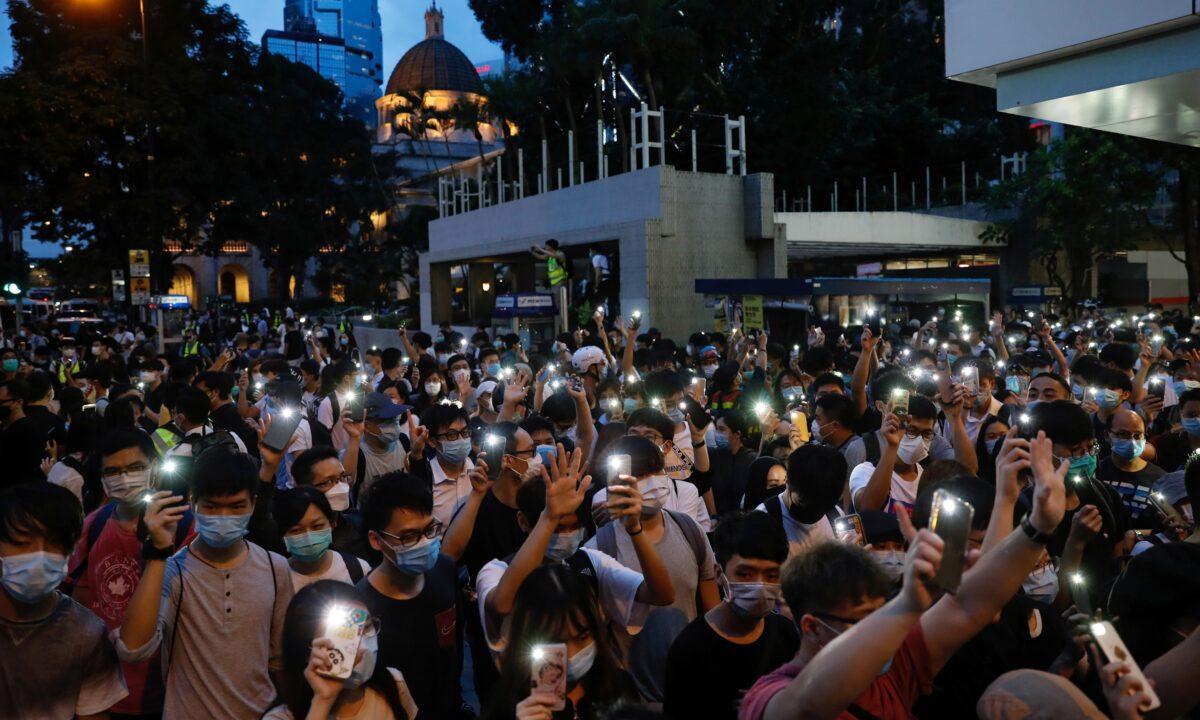 Pro-democracy demonstrators march holding their phones with flashlights on during a protest to mark the first anniversary of a mass rally against the now-withdrawn extradition bill, in Hong Kong on June 9, 2020. (Tyrone Siu/Reuters)