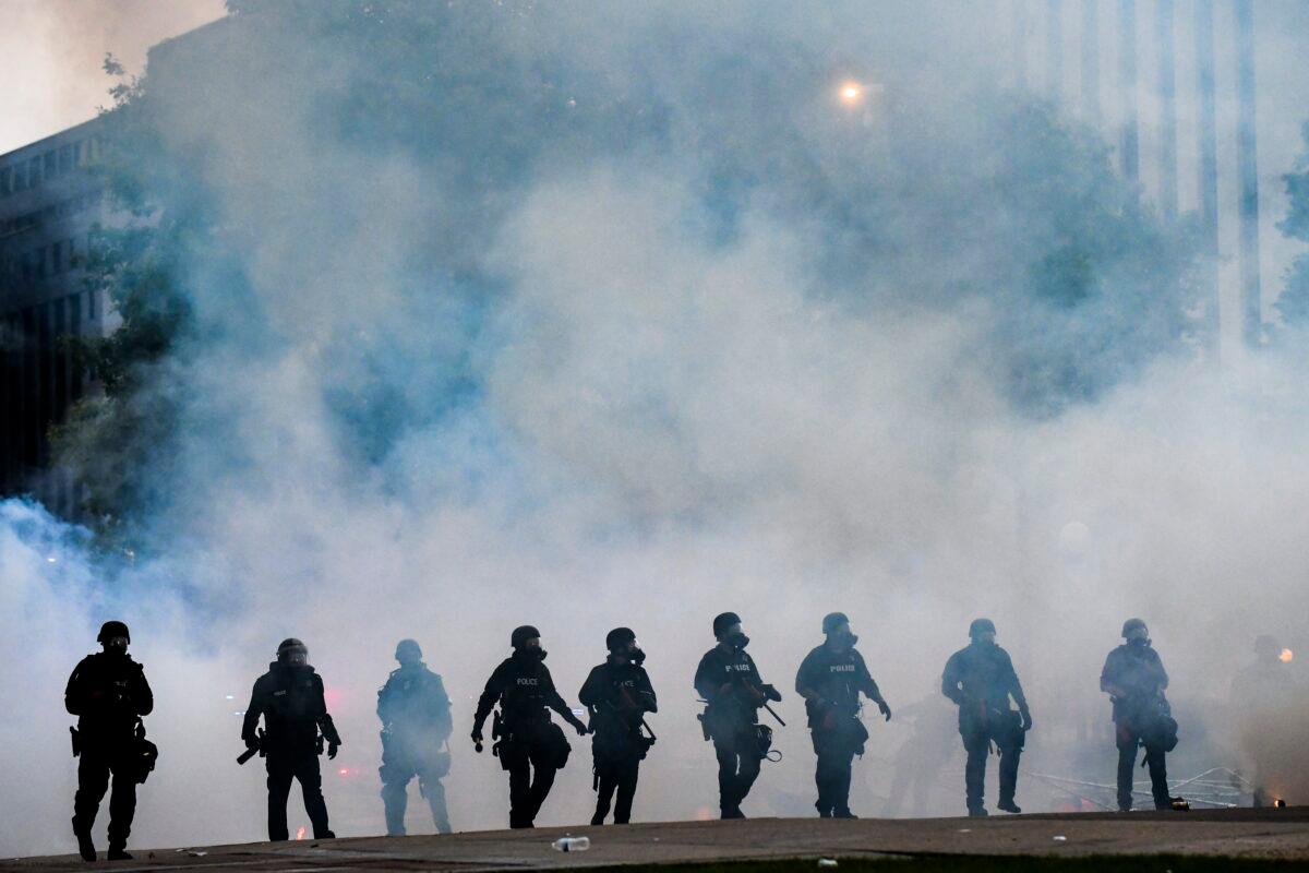 Police officers walk through a cloud of tear gas as they try to disperse people protesting against the death of George Floyd in front of the Colorado State Capitol, in Denver, Colo., on May 30, 2020, amid nationwide protests and riots. (Michael Ciaglo/Getty Images)