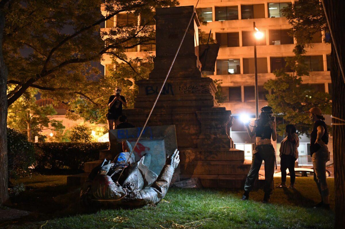 People stand around the statue of Confederate general Albert Pike after it was toppled by vandals in Washington on June 19, 2020. (Eric Baradat/AFP via Getty Images)
