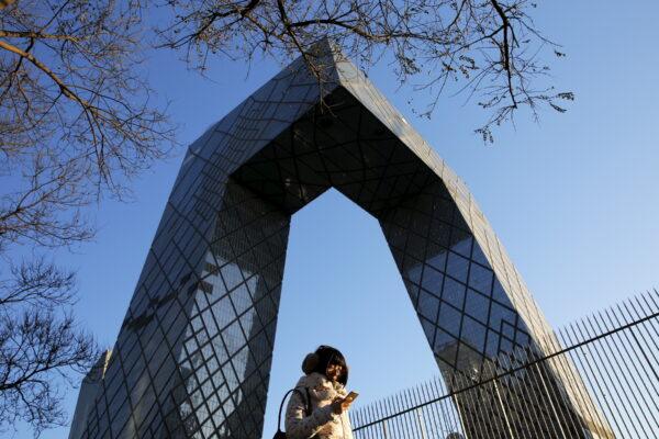 A morning commuter walks in front of the China Central Television (CCTV) building in Beijing on Dec. 2, 2015. (Damir Sagolj/Reuters)