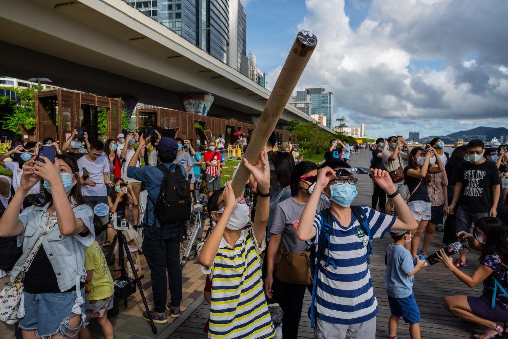 People gather to watch the partial solar eclipse along a promenade on June 21, 2020, in Hong Kong. (Billy H.C. Kwok/Getty Images)