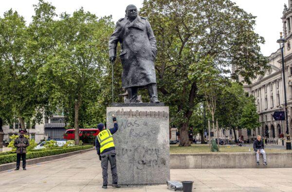 A worker cleans the statue of former prime minister Winston Churchill in London’s Parliament Square that had been spray painted with graffiti during a Black Lives Matter protest on June 8, 2020. (Dan Kitwood/Getty Images)