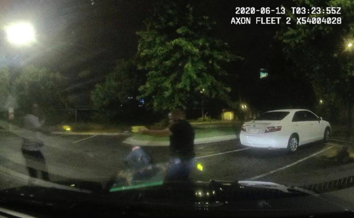 This screen grab taken from dashboard camera video provided by the Atlanta Police Department shows Rayshard Brooks, left, and Officer Garrett Rolfe pointing Tasers at one another, while Officer Devin Brosnan is seen getting up after a struggle among the three men in the parking lot of a Wendy's restaurant in Atlanta, Ga., early June 13, 2020. (Atlanta Police Department via AP)