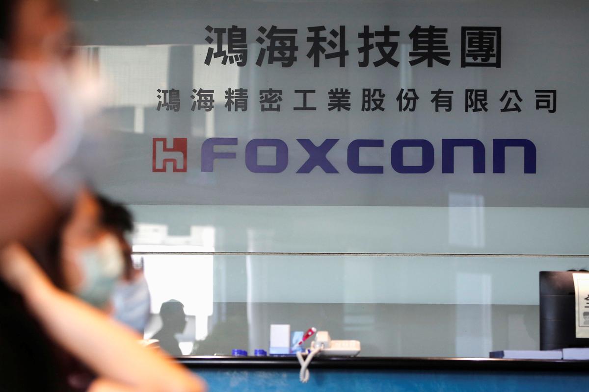 People wear face masks while listening to the annual general meeting at the lobby of Foxconn's office in Taipei, Taiwan, June 23, 2020. The company, an Apple supplier, has decided to invest $1 billion to expand a factory in India. (Ann Wang/Reuters)