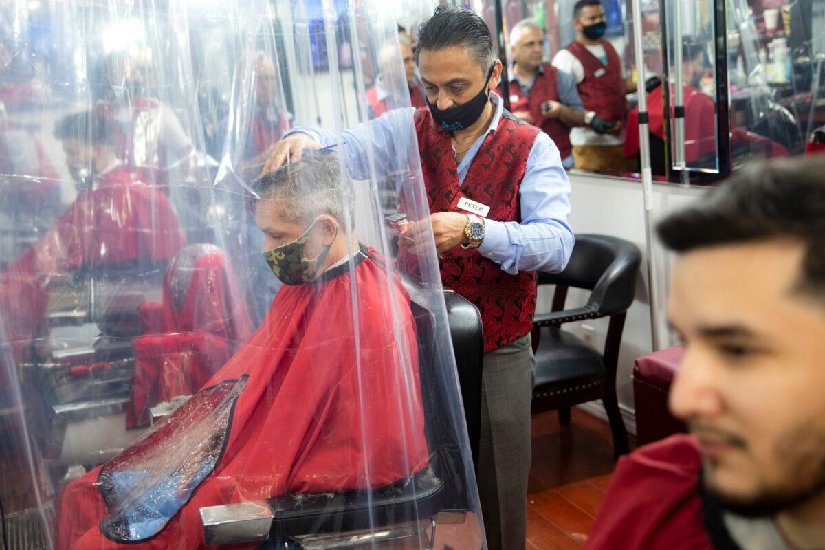Peter Shamuelov (C) wears a protective mask as he gives a haircut to a customer at Ace of Cuts barbershop, in New York City on June 22, 2020. (John Minchillo/AP Photo)
