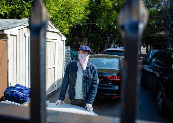 Steve Snook, a pastor at Metropolis Church in Santa Monica, Calif., wears a facial covering as he hands out bags of food to low-income individuals near his church, on June 22, 2020. (John Fredricks/The Epoch Times)