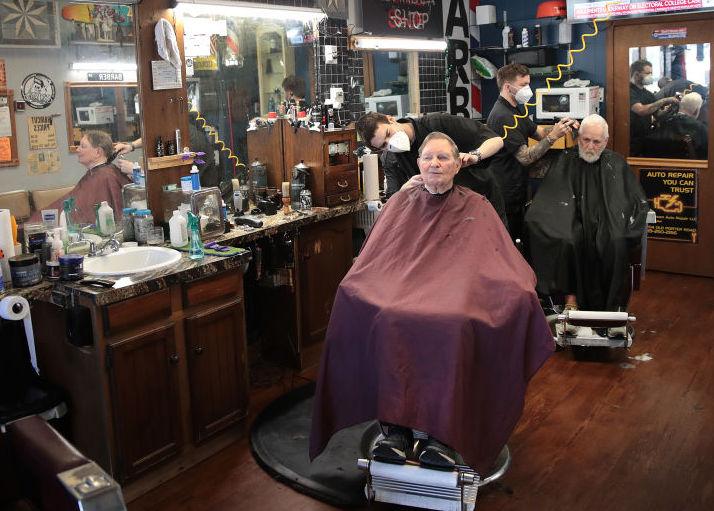 (Right) Barbers Steve Grimaldi (L) and Chris Pouch cut hair for customers at Grimaldi's Barber Shop in Chesterton, Ind., on May 13, 2020. (Scott Olson/Getty Images)