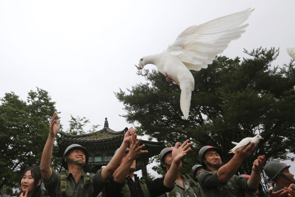 Actors wearing military uniforms release pigeons during a ceremony to mark the 70th anniversary of the outbreak of the Korean War in Cheorwon, near the border with North Korea, South Korea, on June 25, 2020. (Ahn Young-joon/AP Photo)
