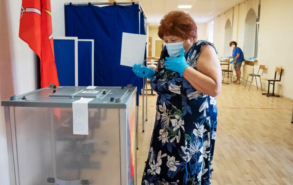 A voter wearing a face mask and protective gloves to protect against coronavirus walks to cast her ballot at a polling station in St.Petersburg, Russia, on June 25, 2020. (Dmitri Lovetsky/AP Photo)