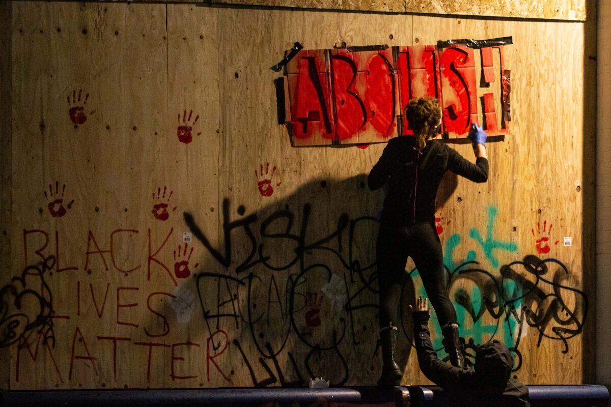 People paint the exterior of the Seattle Police Department's abandoned East Precinct in Seattle, Wash., on June 19, 2020. (David Ryder/Getty Images)