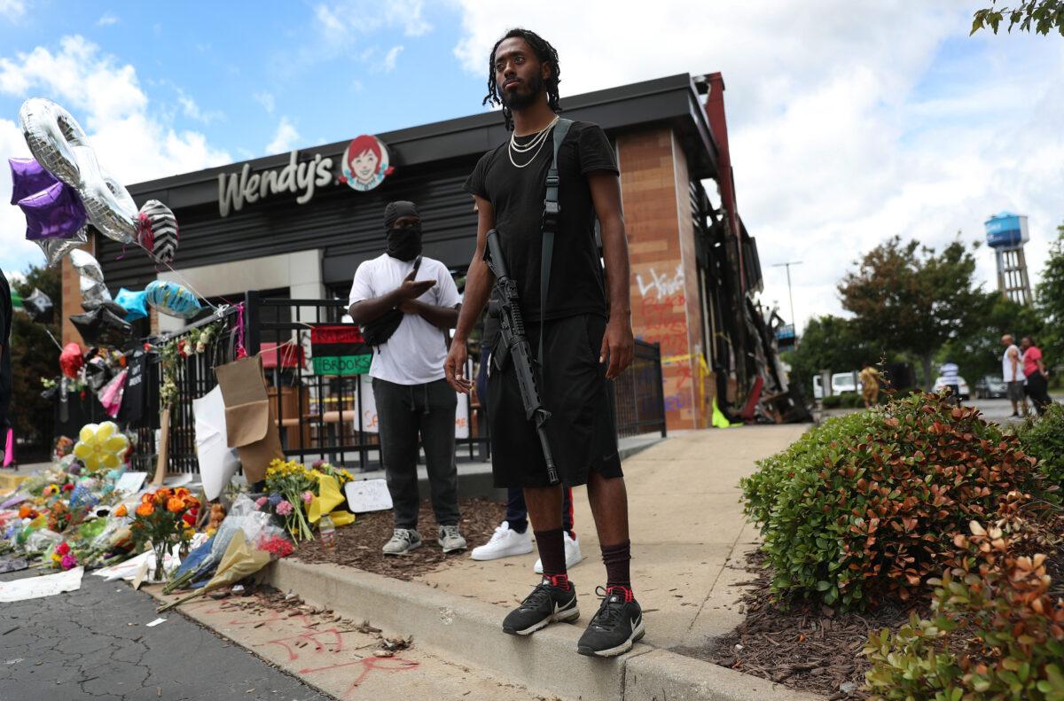 A man armed with a rifle stands guard at the memorial that has grown around the Wendy's restaurant that was set on fire after Rayshard Brooks was killed, in Atlanta, Ga., on June 16, 2020. (Joe Raedle/Getty Images)