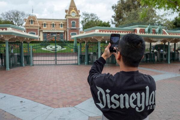 A man takes a photo outside the gates of Disneyland Park on the first day of the closure of Disneyland and Disney California Adventure theme parks due to the spread of COVID-19 in Anaheim, Calif., on March 14, 2020. (David McNew/AFP via Getty Images)