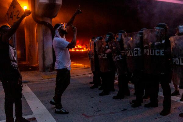 Protesters confront riot police in front of a burning police car during a protest against police brutality in Miami on May 30, 2020. (Adam DelGiudice/AFP via Getty Images)