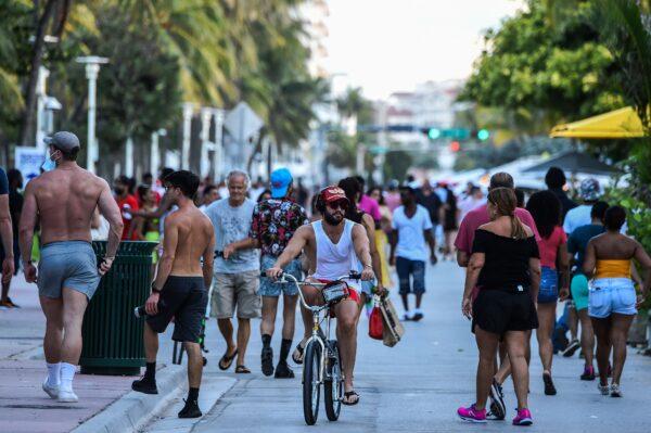 A man rides a bicycle as people walk on Ocean Drive in Miami Beach, Fla., on June 26, 2020. (Chandan Khanna/AFP/Getty Images)